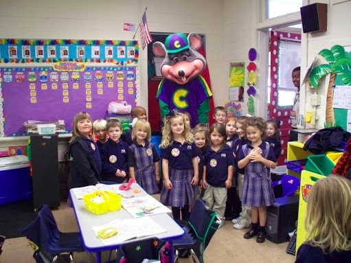 Little fans of Chuck E Cheese around the costumed mascot during a school visit